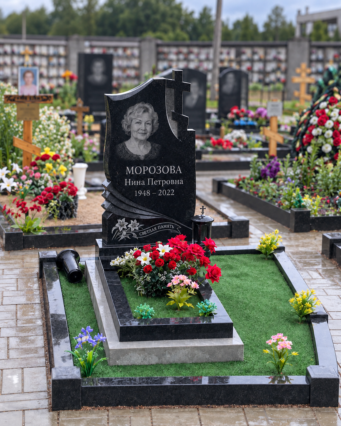 Фигурная стела и зелёное покрытие после установки на участке. Имена, даты и портреты изменены.