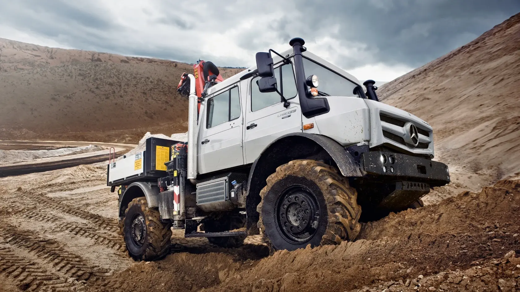 Белый Unimog едет по песчаной местности