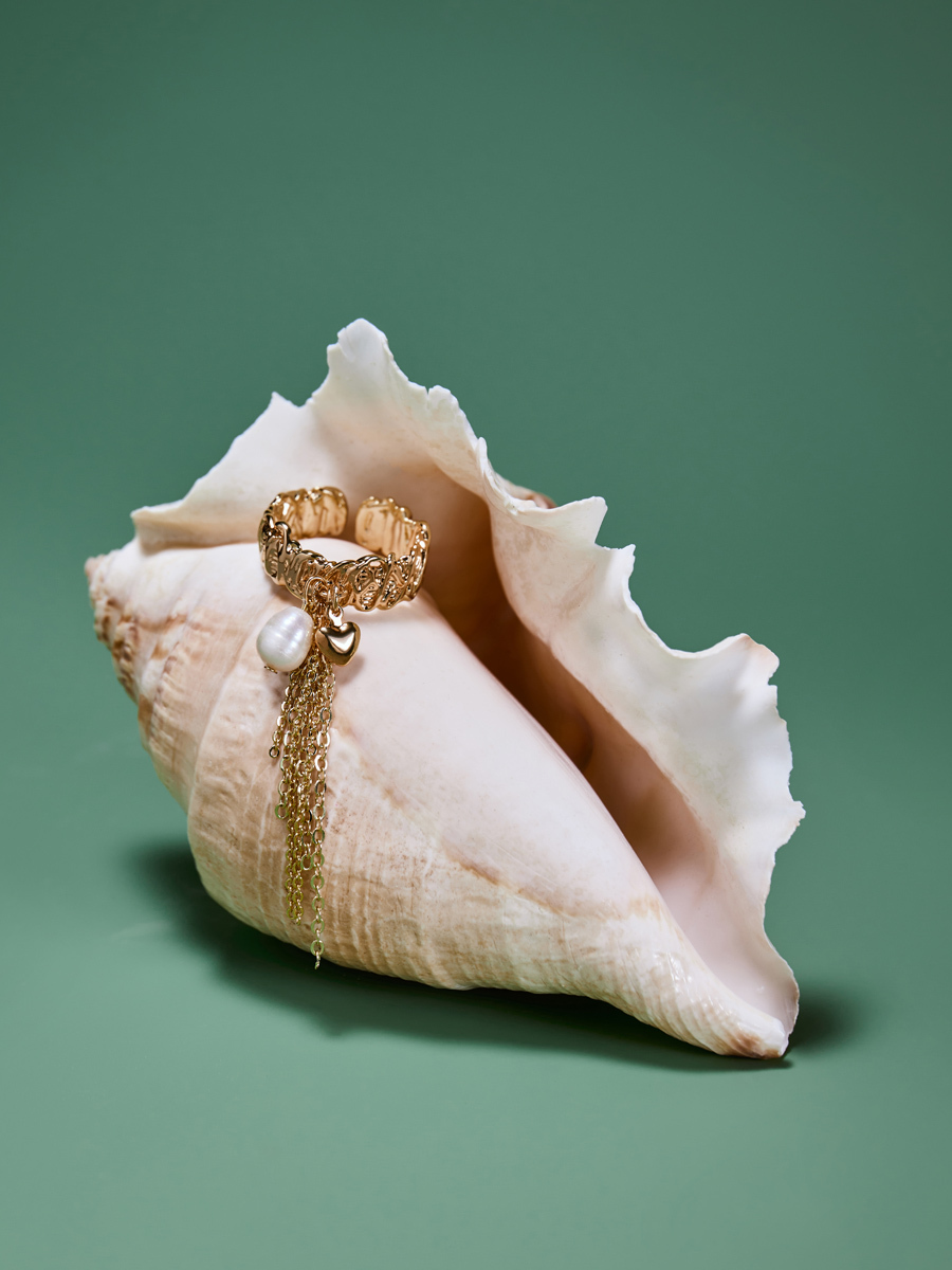 золотое кольцо на ракушке на зеленом фоне съемка