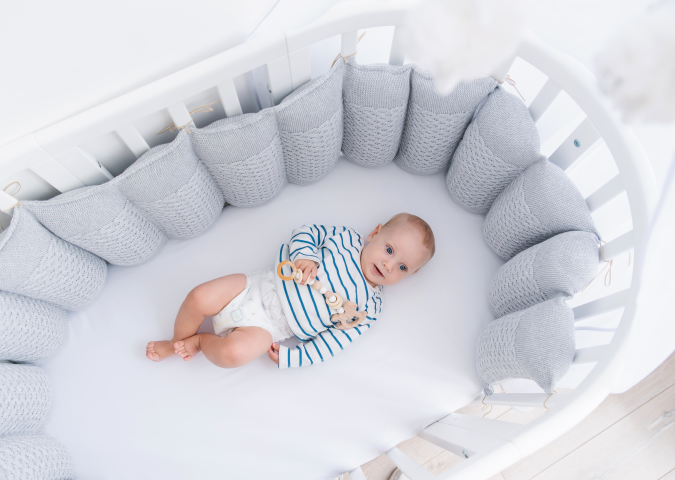 ребенок лежит в кроватке с бортиками