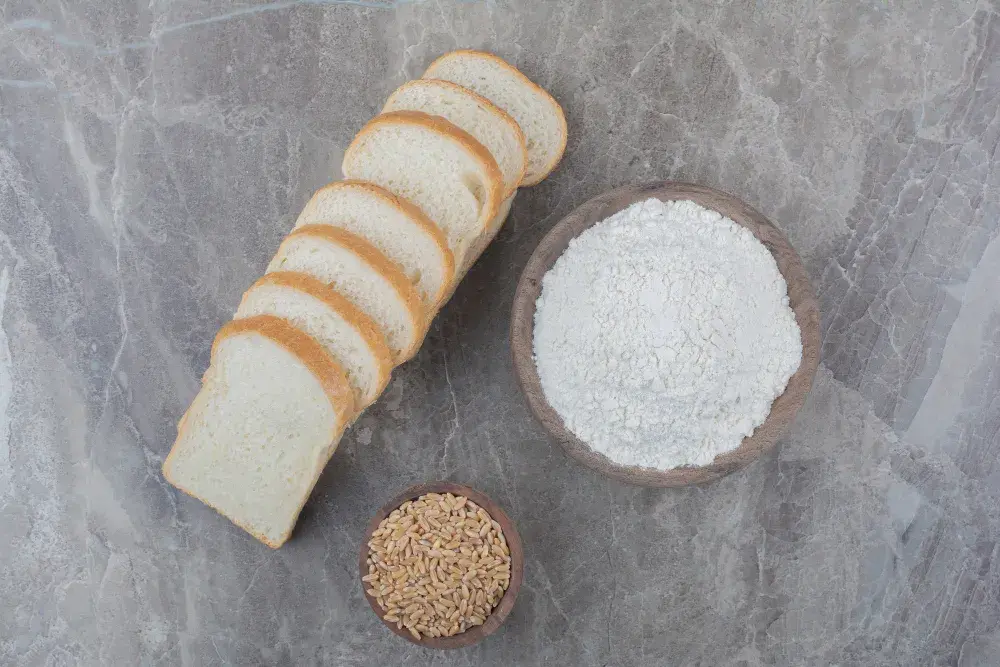 Куски белого хлеба на столе с мукой и зёрнами