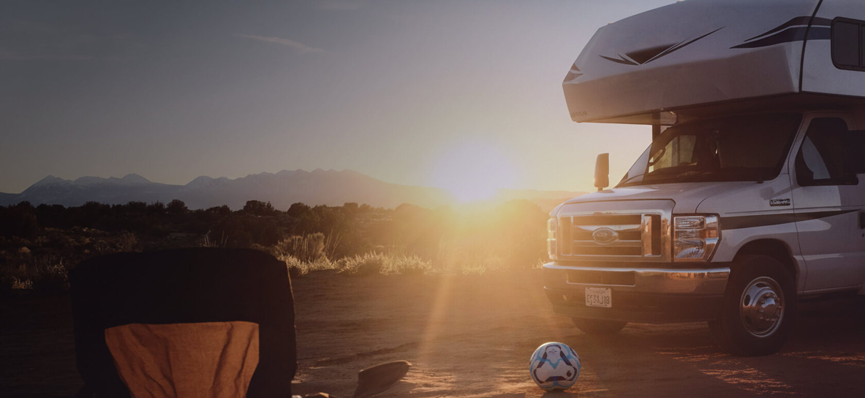 Autocaravana decorada con banderas de diferentes países de fútbol aparcada cerca de un moderno estadio.