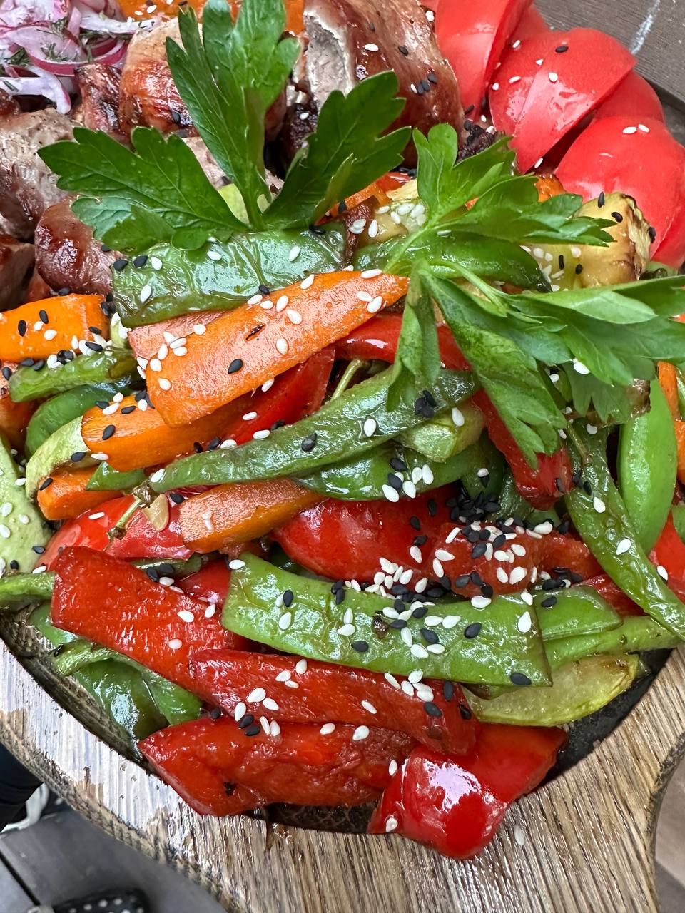 Приготовленные в казане морковь, перец и зелёные овощи рядом с горячим блюдом