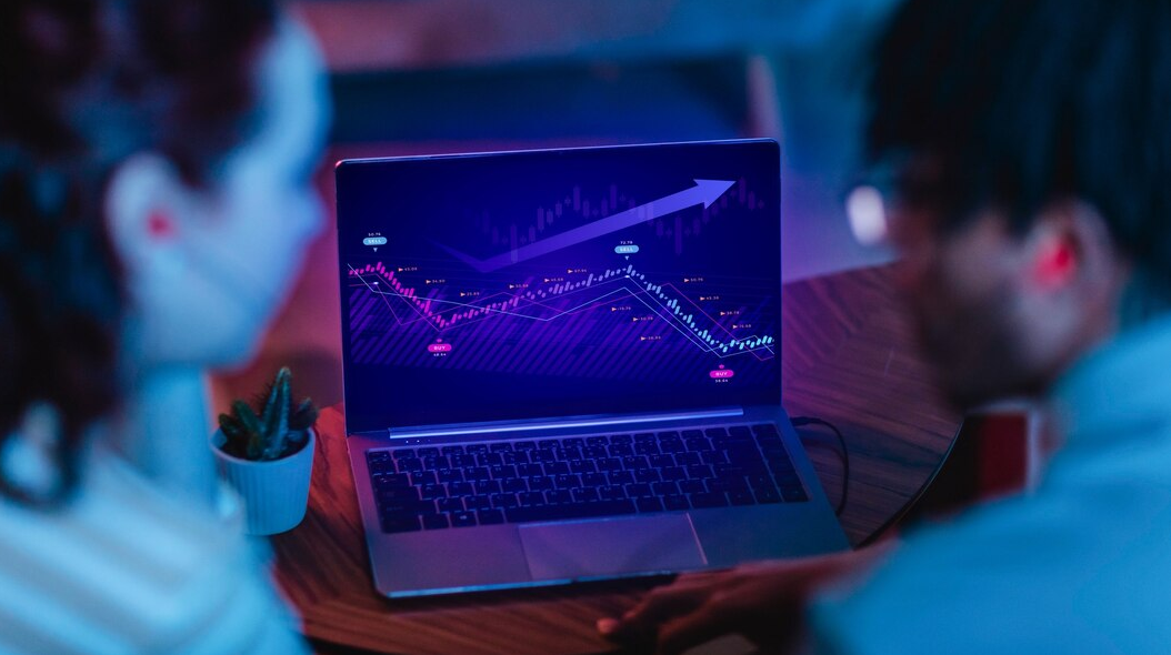 What is the futures market: trading futures is represented by a photograph of two traders in front of a laptop featuring a crypto trading chart