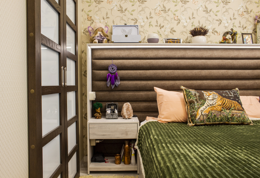 текстильное большое изголовье кровати с верхней полкой, обои в цветочек и деревянные раздвижные двери со стеклом