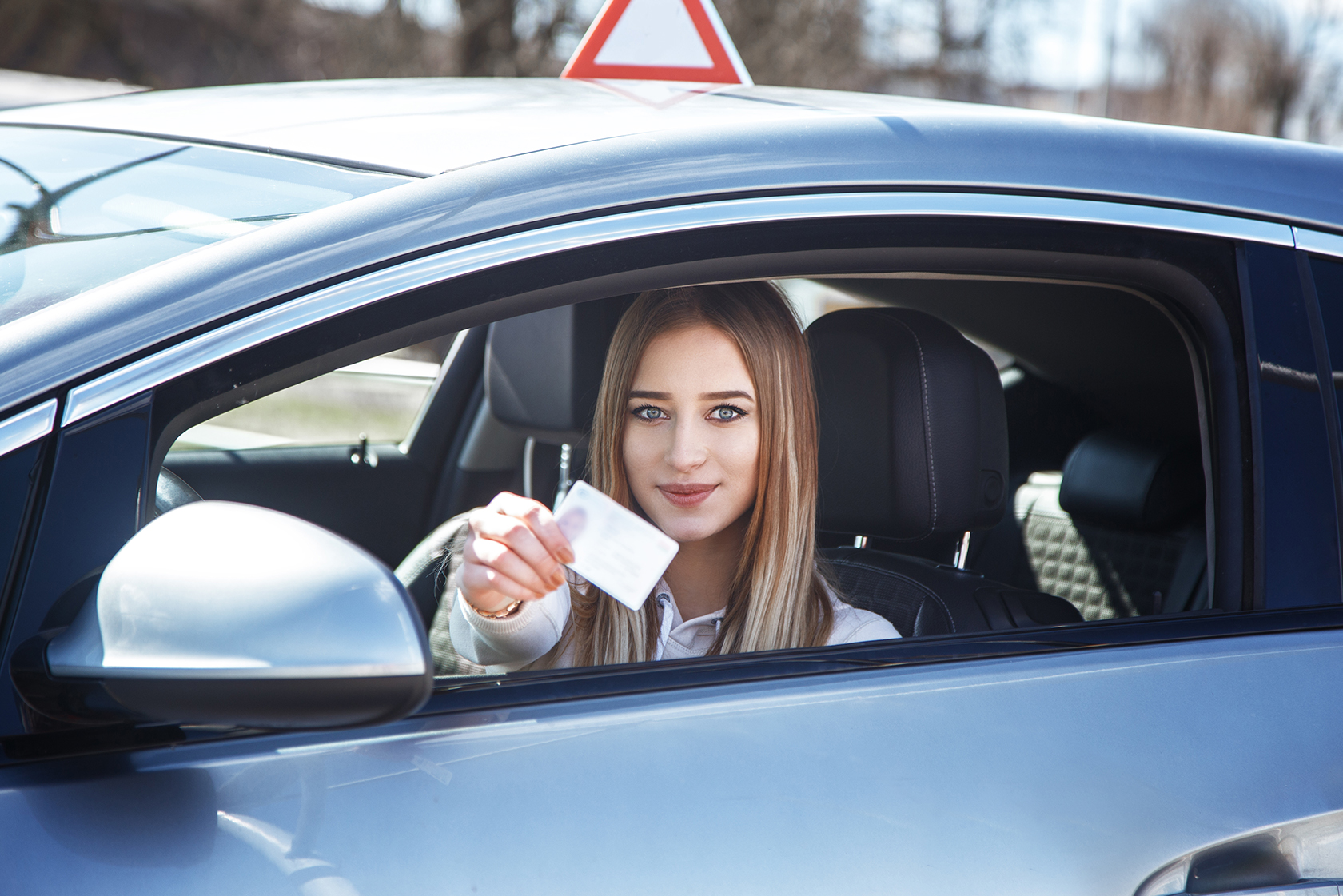 Водительское удостоверение и девушка за рулем