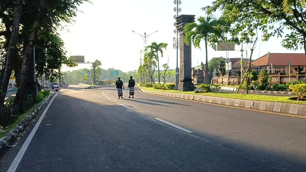 Two traditional Pecalang security guards walking down a completely deserted highway, ensuring the island remains silent during the Nyepi celebration.
