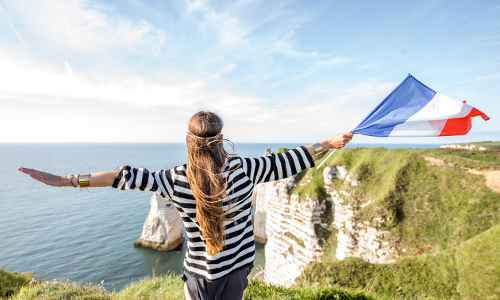 Девушка размахивает французским флагом на скалах в Этрета