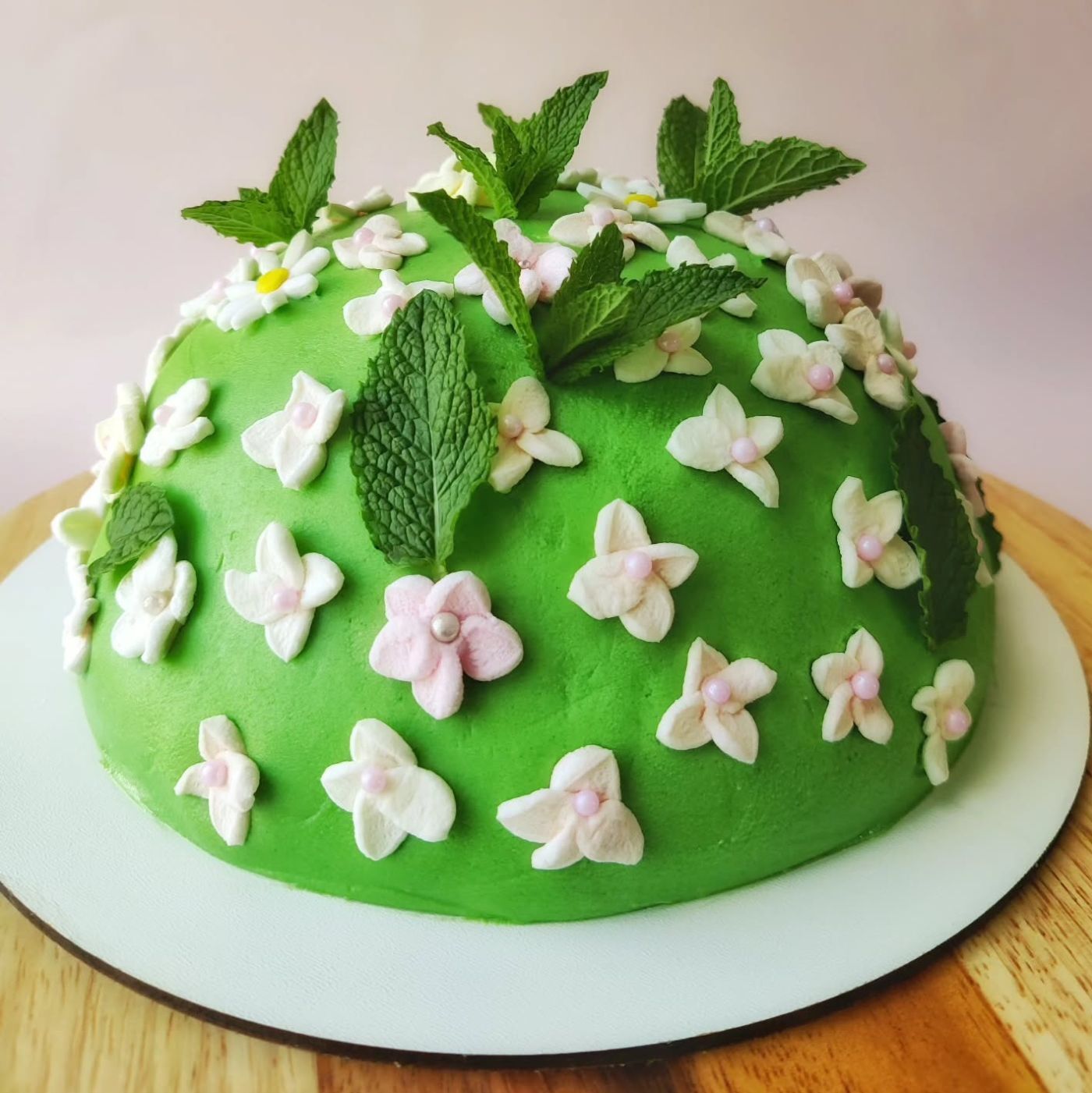 Narodeninová piškótová torta v tvare jarného trávnika s kvetmi a čerstvou mätou
