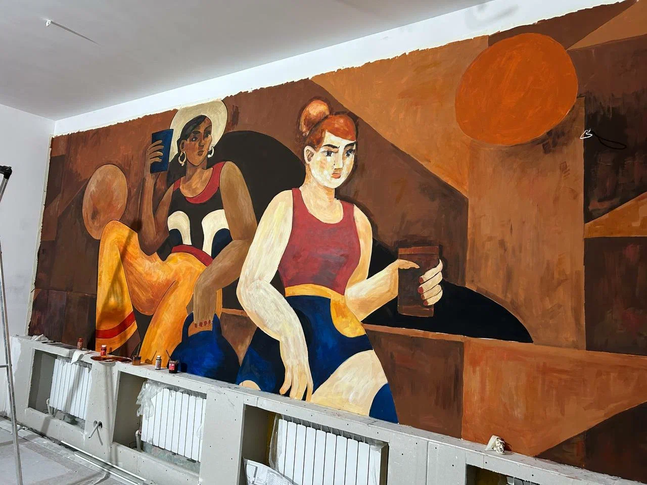 Художник ArtWorker прорабатывает оттенки на росписи стены в кофейне
