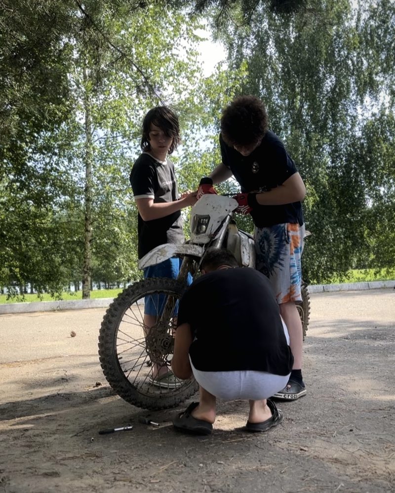 Подростки обслуживают мотоцикл на площадке