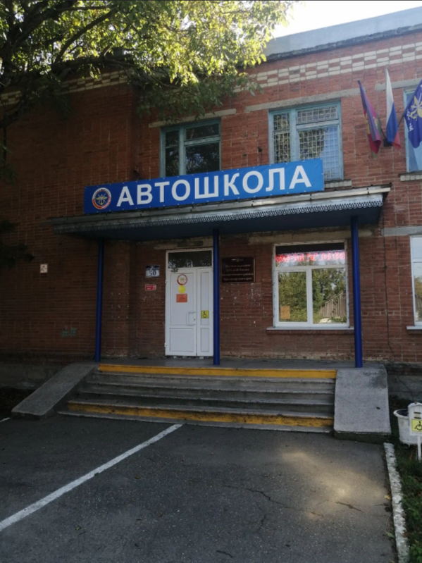 Фасад автошколы ДОСААФ с российским флагом и лестницей