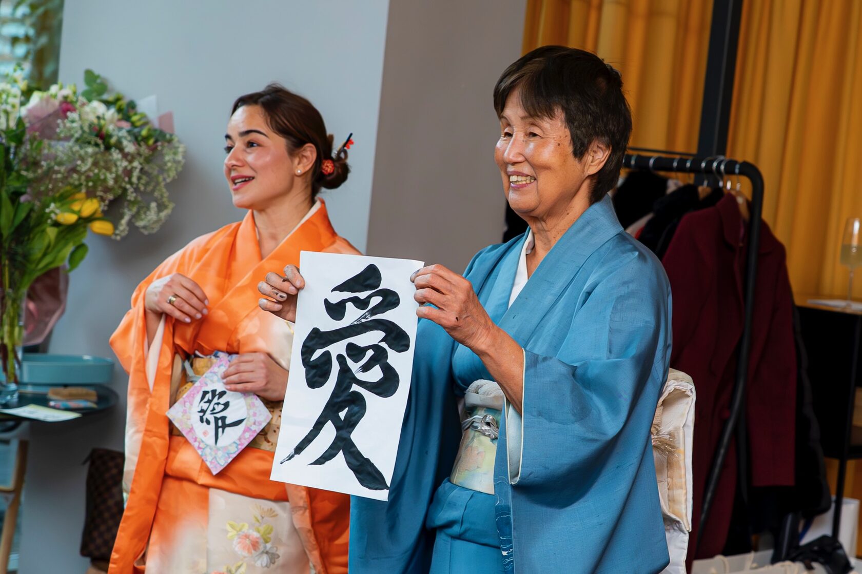 Японски гост и дама в кимоно представят калиграфски символ пред участничките в събитието.