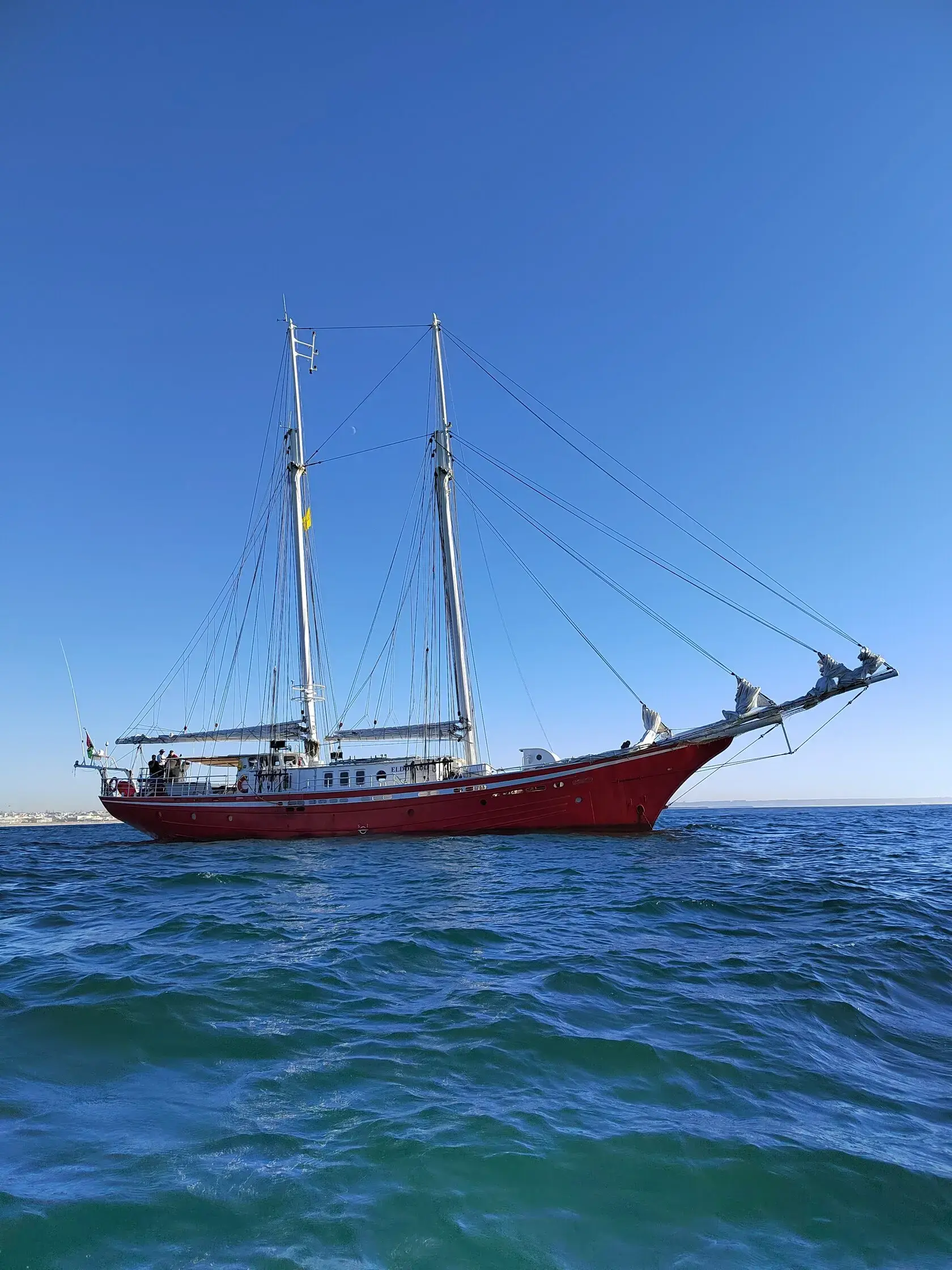 The two-masted schooner Eldorado sailing across the open sea under a clear blue sky. Built for long-distance ocean crossings and polar expeditions the 38-meter sailing ship carries just 12 guests and is used by MoreTime Expeditions for Great Sailing voyag