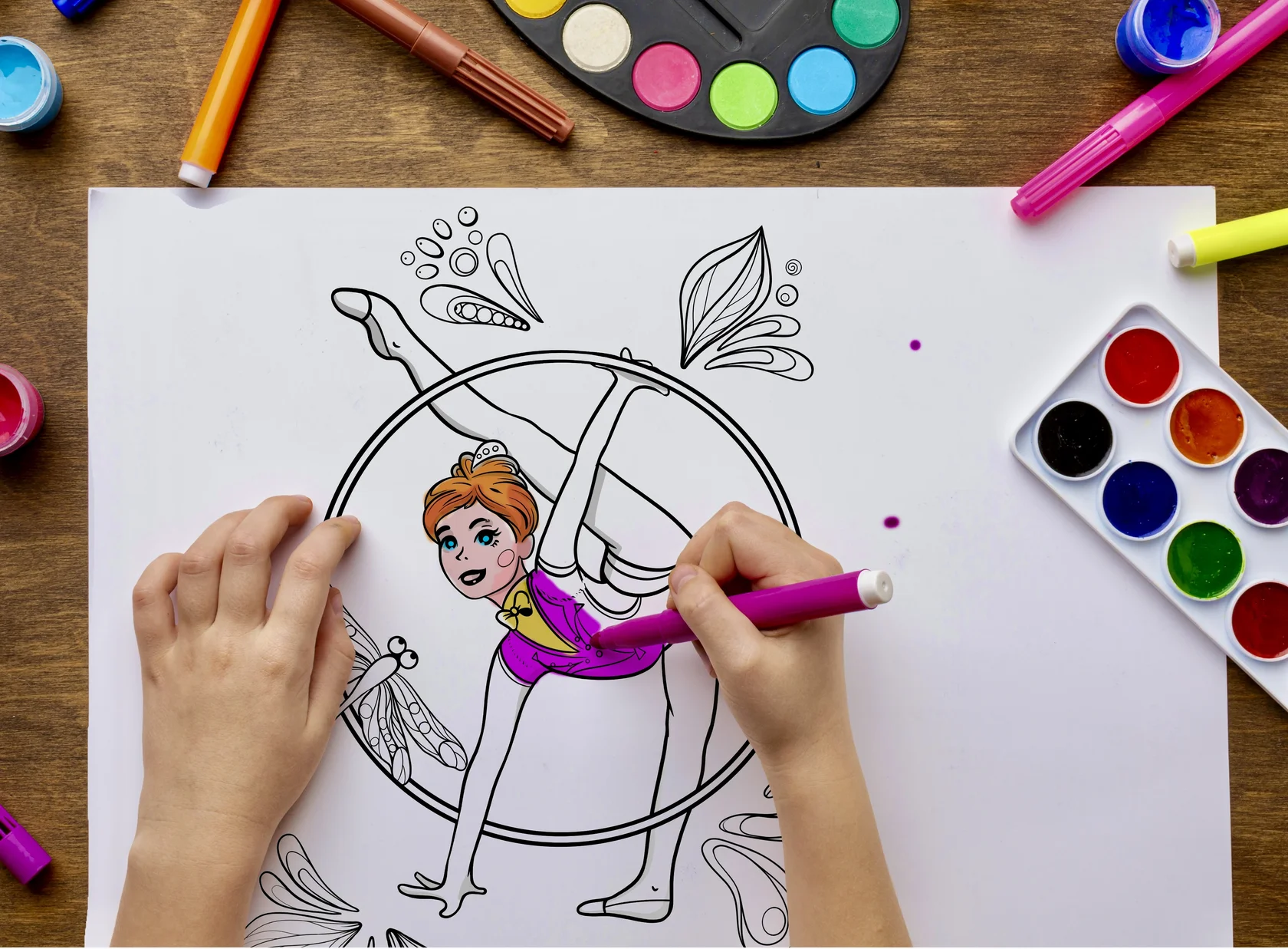 Child coloring a rhythmic gymnastics page with paints and markers