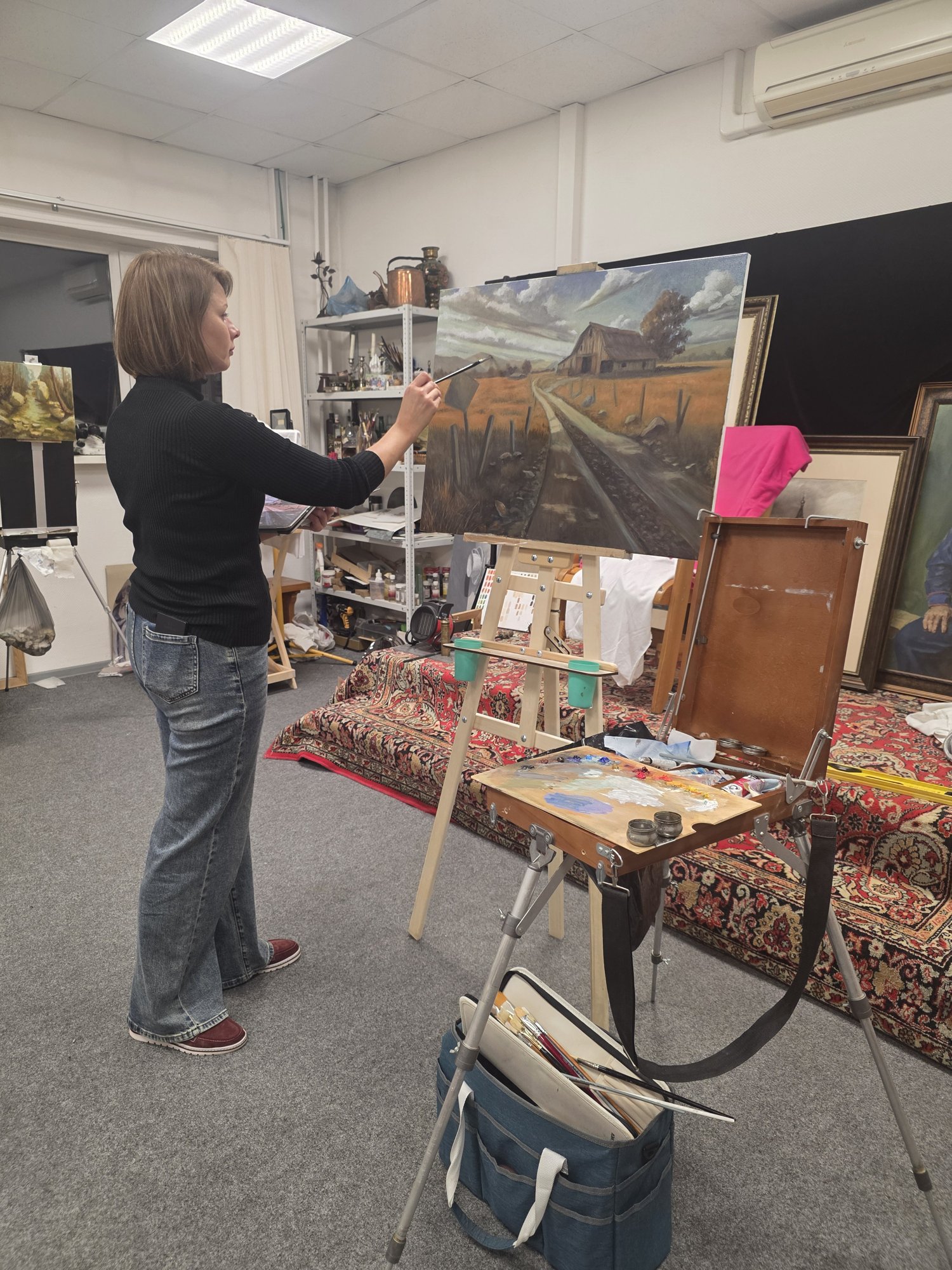 Ученица пишет маслом пейзаж с сельской дорогой и амбаром в мастерской ABC Art School