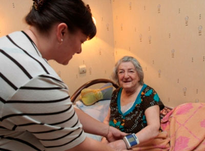 Сиделка измеряет давление пожилой женщине