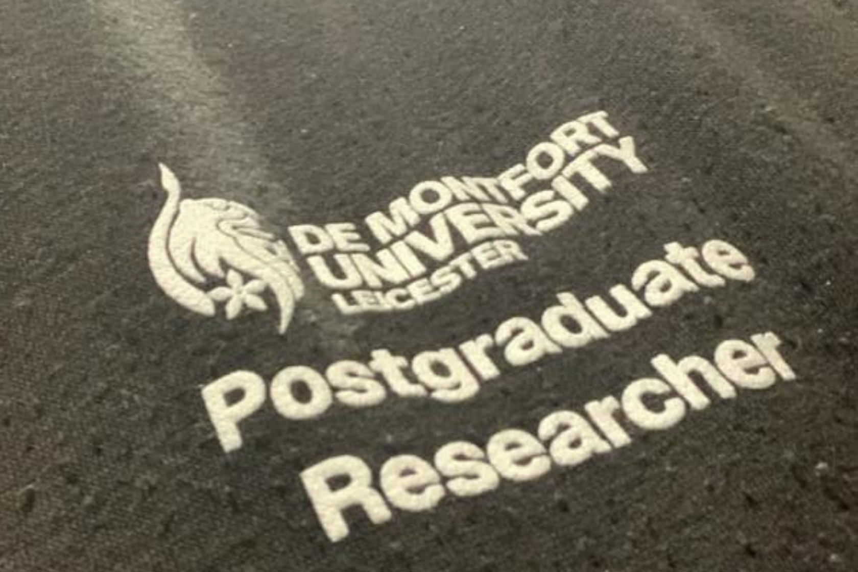 De Montfort University postgraduate researcher badge on a black fabric