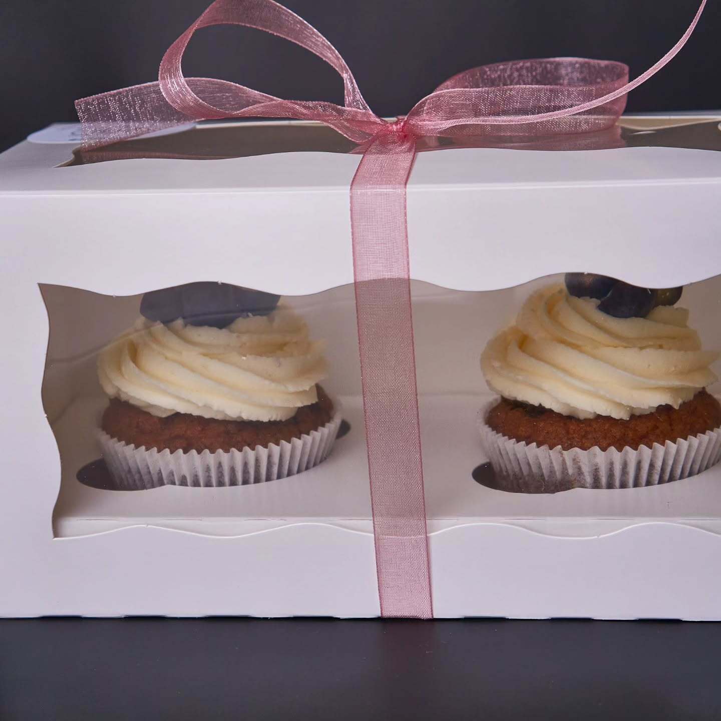 Dva muffiny v elegantnej krabičke s priehľadným vekom, pripravené ako darček