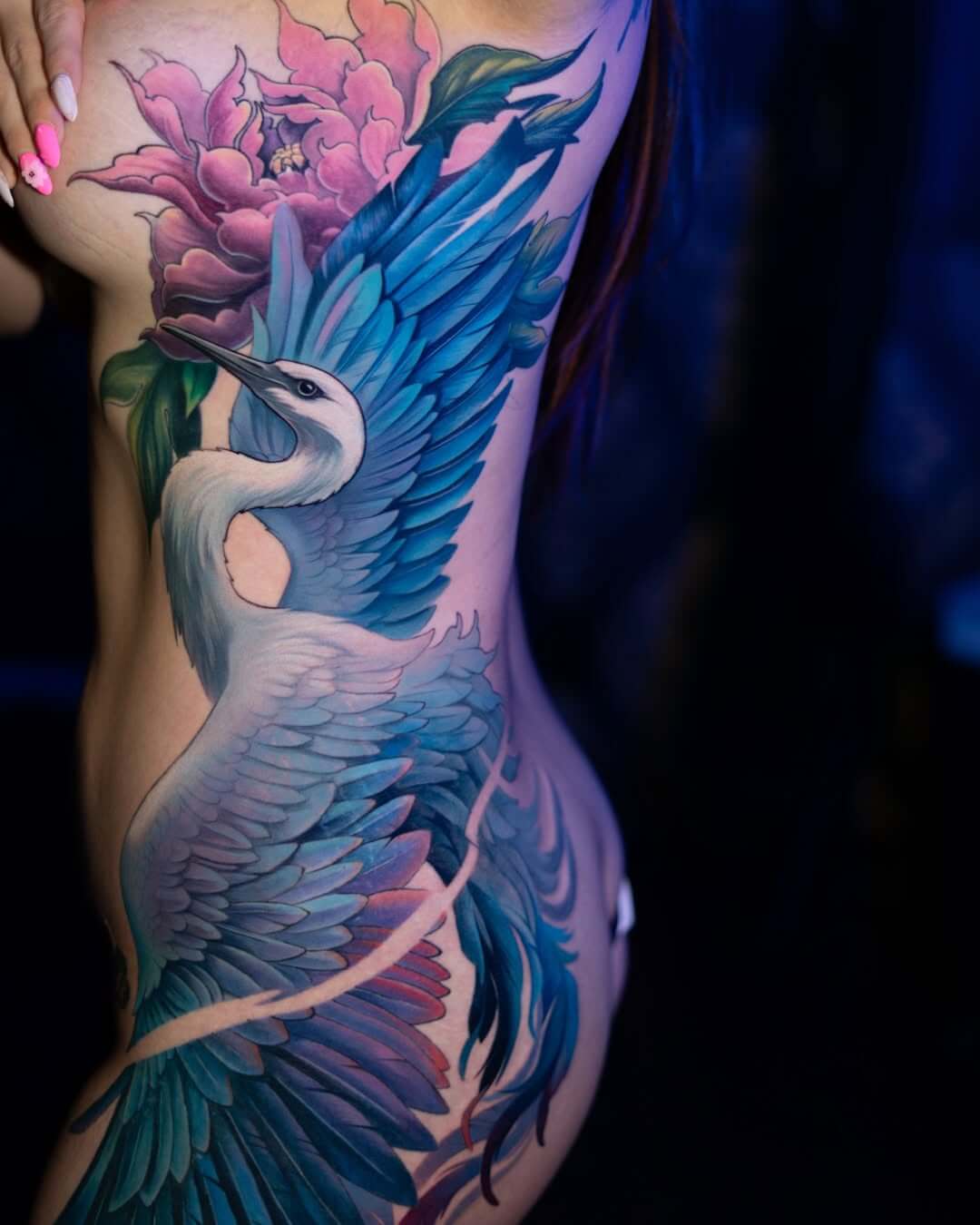 Full side body tattoo of a blue-winged crane and a purple peony, colorful Japanese-inspired realism.
