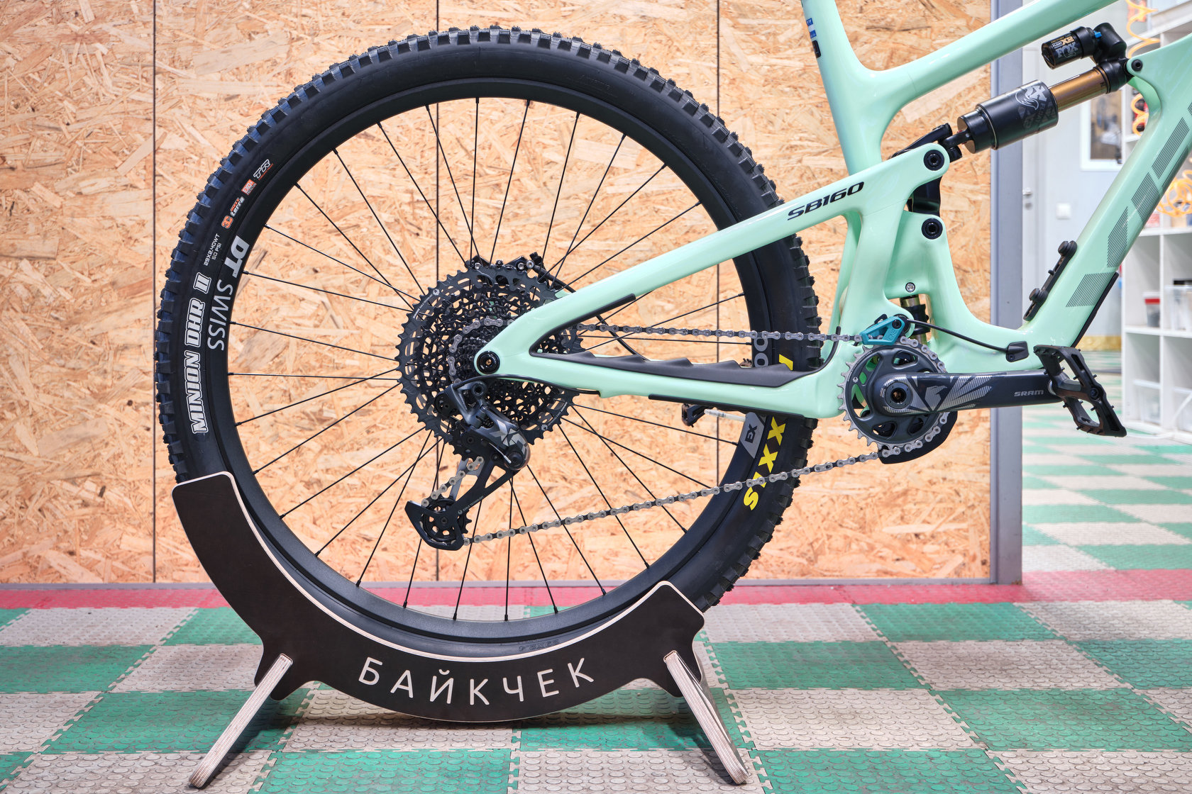 Заднее колесо велосипеда Yeti SB160 в деревянной подставке с надписью Байкчек в мастерской