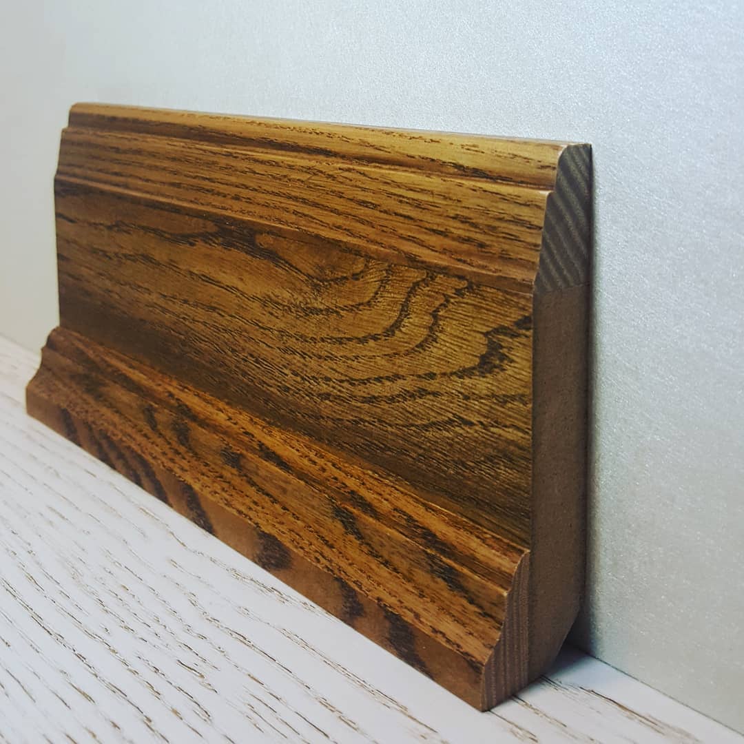 Массивный деревянный плинтус с глубоким оттенком, гармонично вписывающийся в классическую обстановку комнаты.