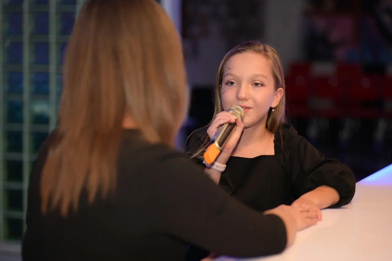 Маленькая девочка обучается вокалу с преподавателем