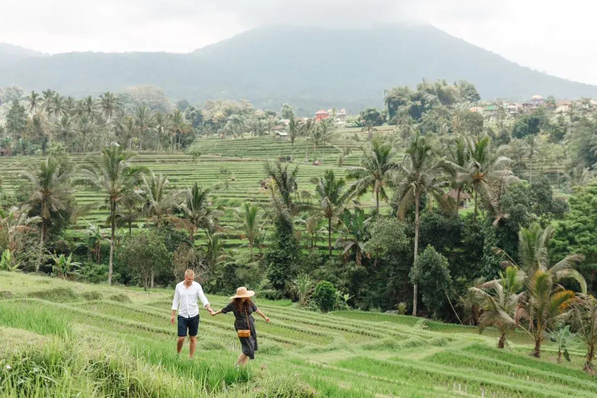 A couple enjoying a romantic walk in the green rice terraces, a perfect early evening start when planning what to do in Ubud at night.
