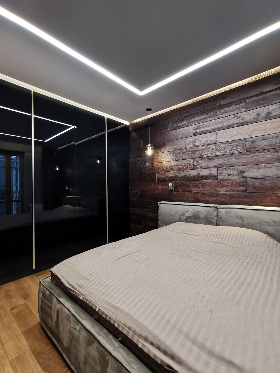 стена из досок, серая кровать, чёрный стеклянный шкаф, линейный светильник