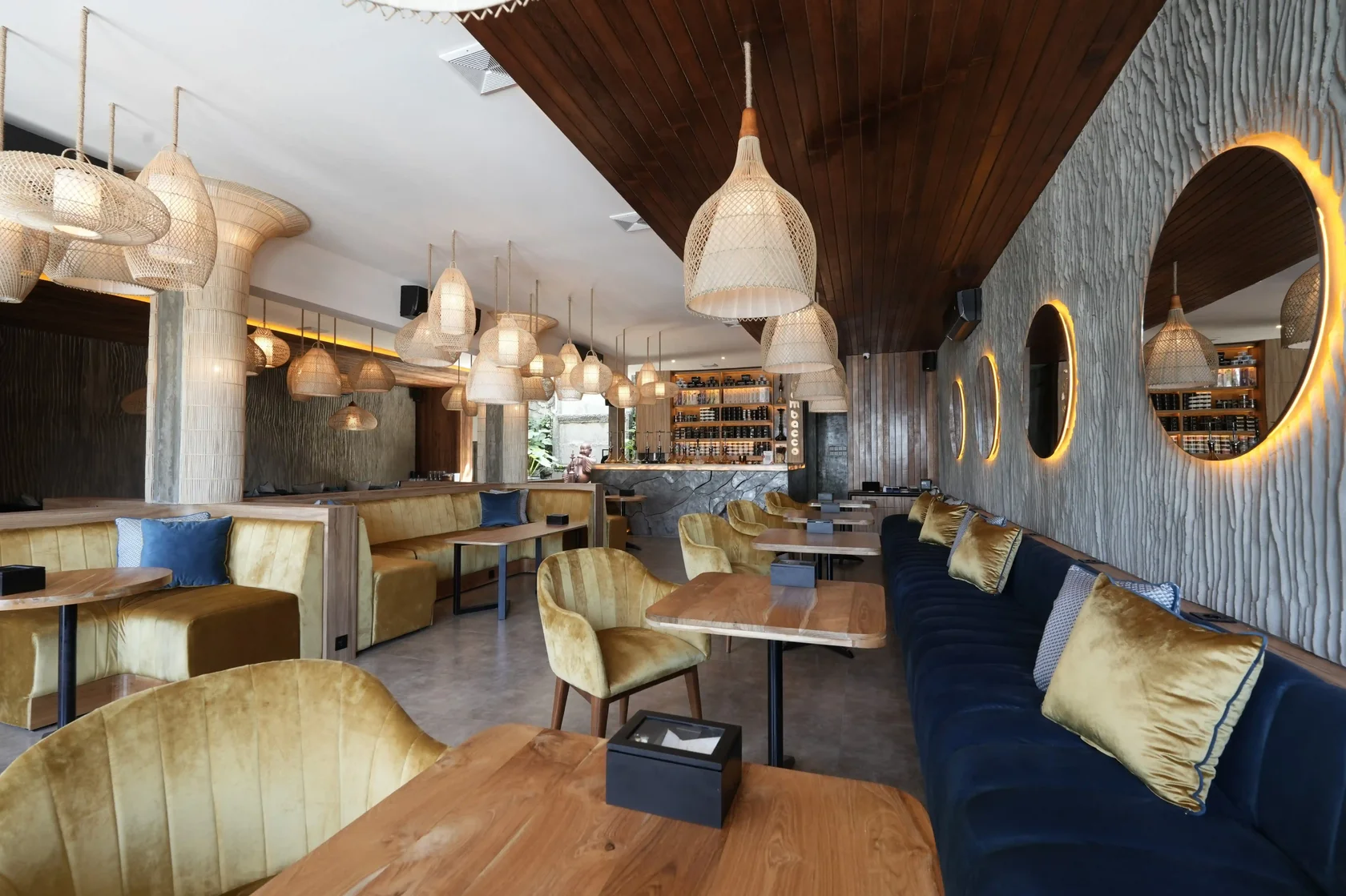 Eden Hookah Club Uluwatu dining area with wooden tables, velvet seating and woven pendant lights