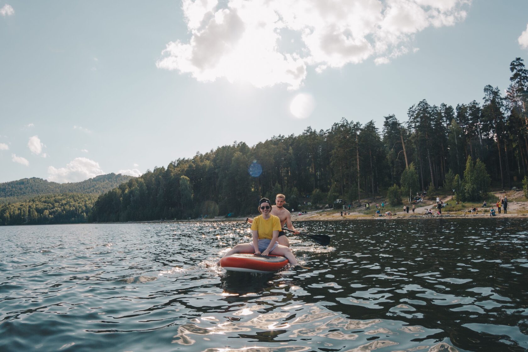 парень и девушка сидят на сапе и плавают по озеру Аракуль