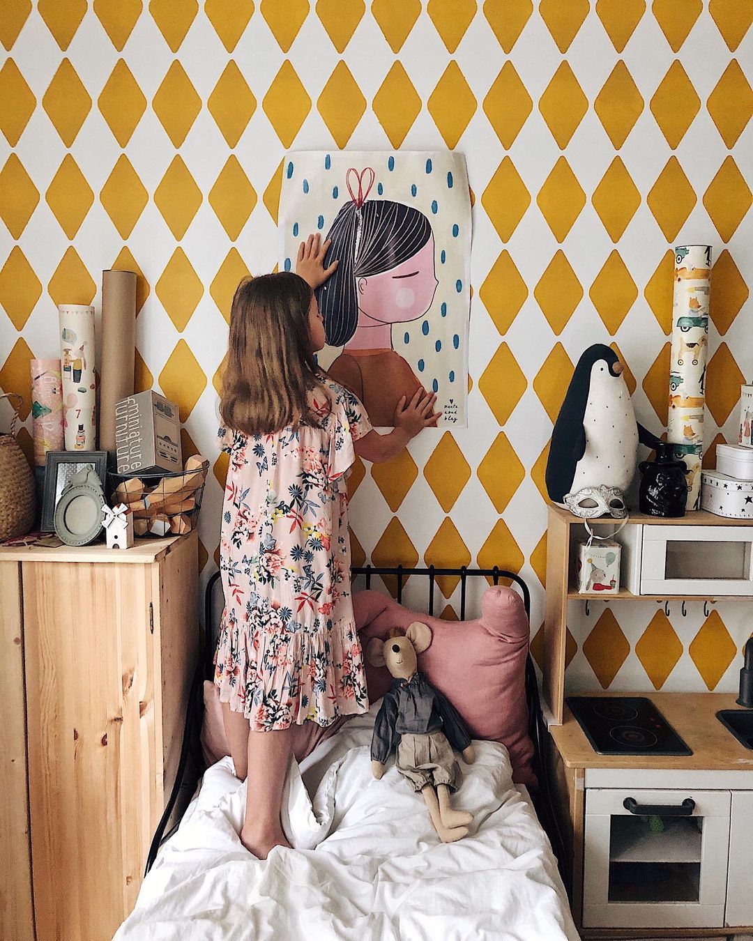 девочка клеит постер у себя в детской комнате