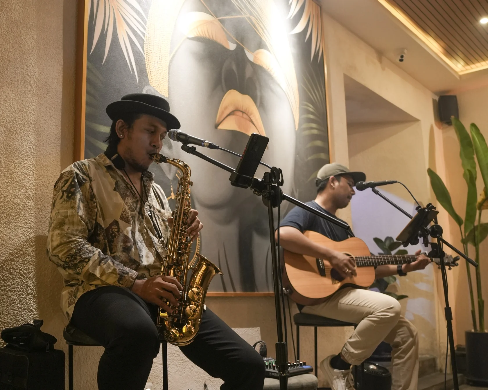 Talented musicians playing acoustic guitar and saxophone to entertain the crowd during a relaxed pre party in Canggu.