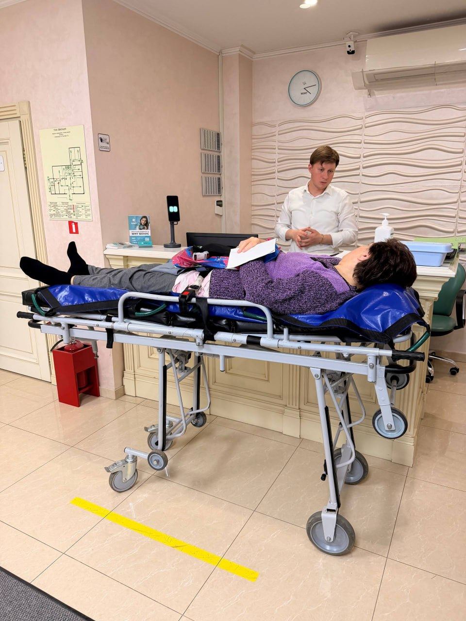 Пациентка на каталке у стойки приёмного покоя