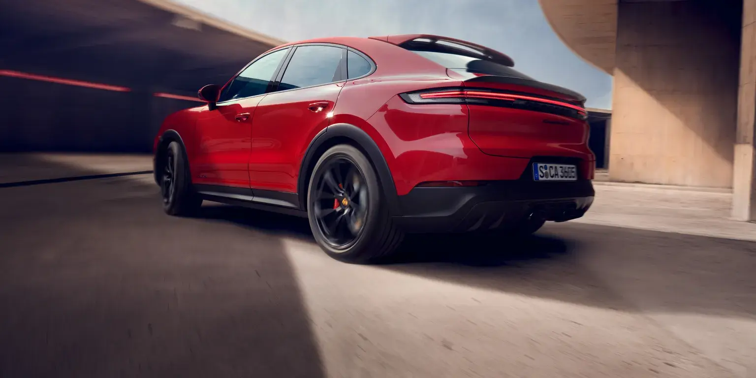 Вид сзади и сбоку на движущийся Porsche Cayenne GTS Coupé