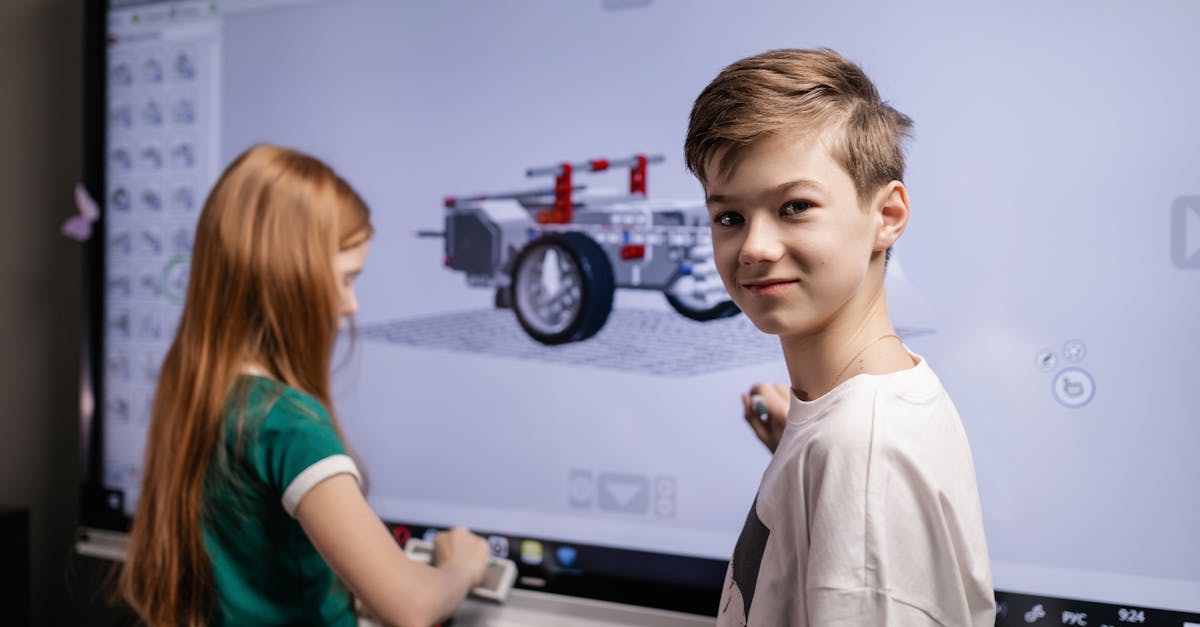 Дети работают вместе за электронной доской на уроке программирования. На доске изображена разработанная 3Д моедль автомобиля.