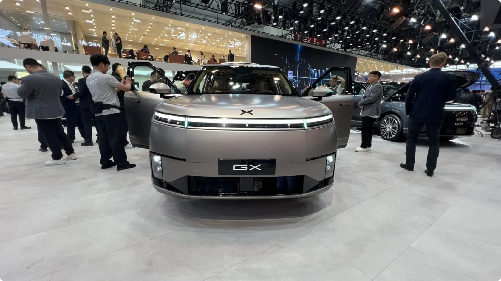 Xpeng GX на автосалоне: сквозная световая полоса, агрессивный бампер и массивная решетка радиатора, вид спереди.