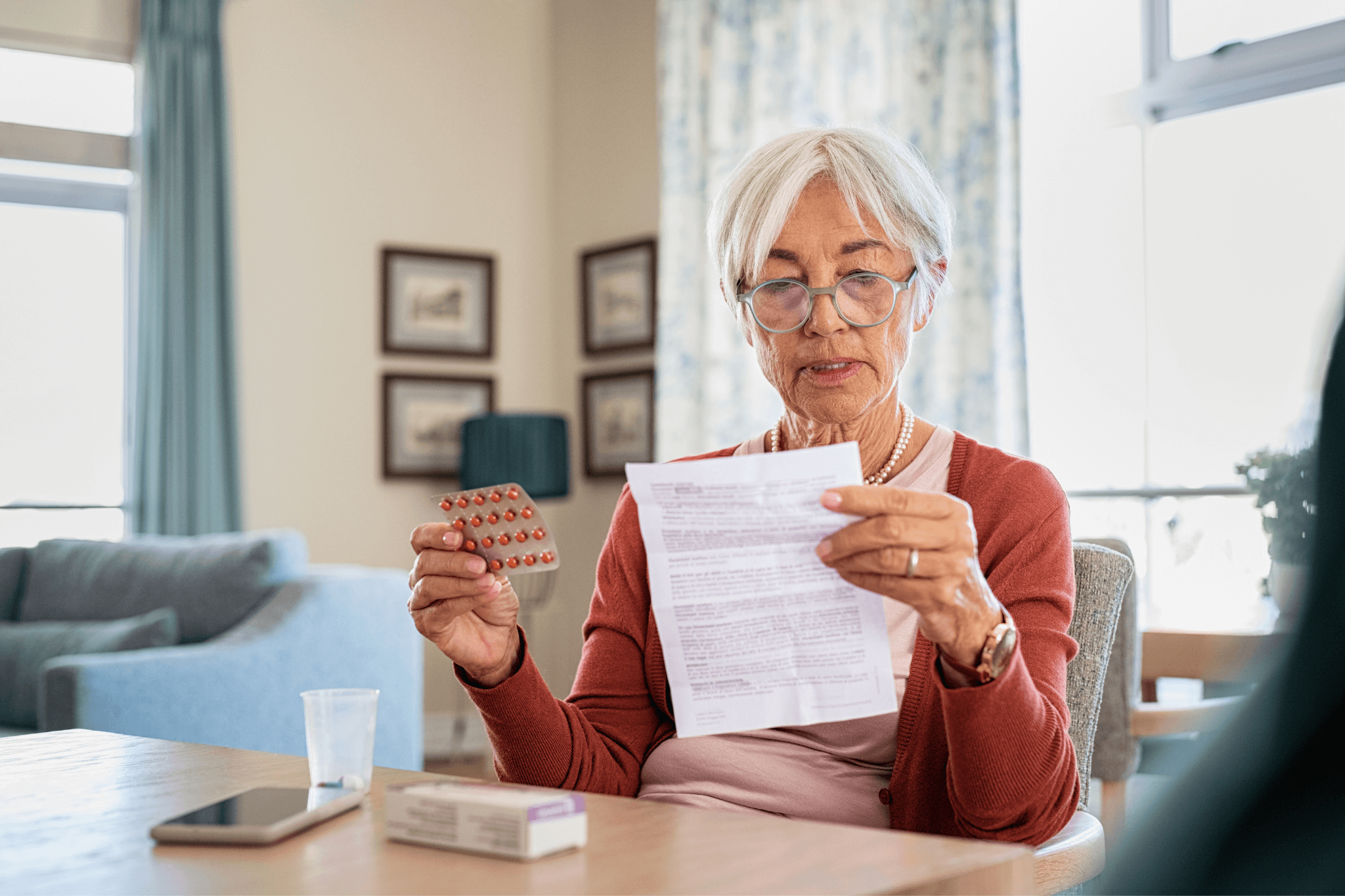 Patientin im Seniorenalter hält Arzneimittelpackung in der Hand und lliest die Packungsbeilage
