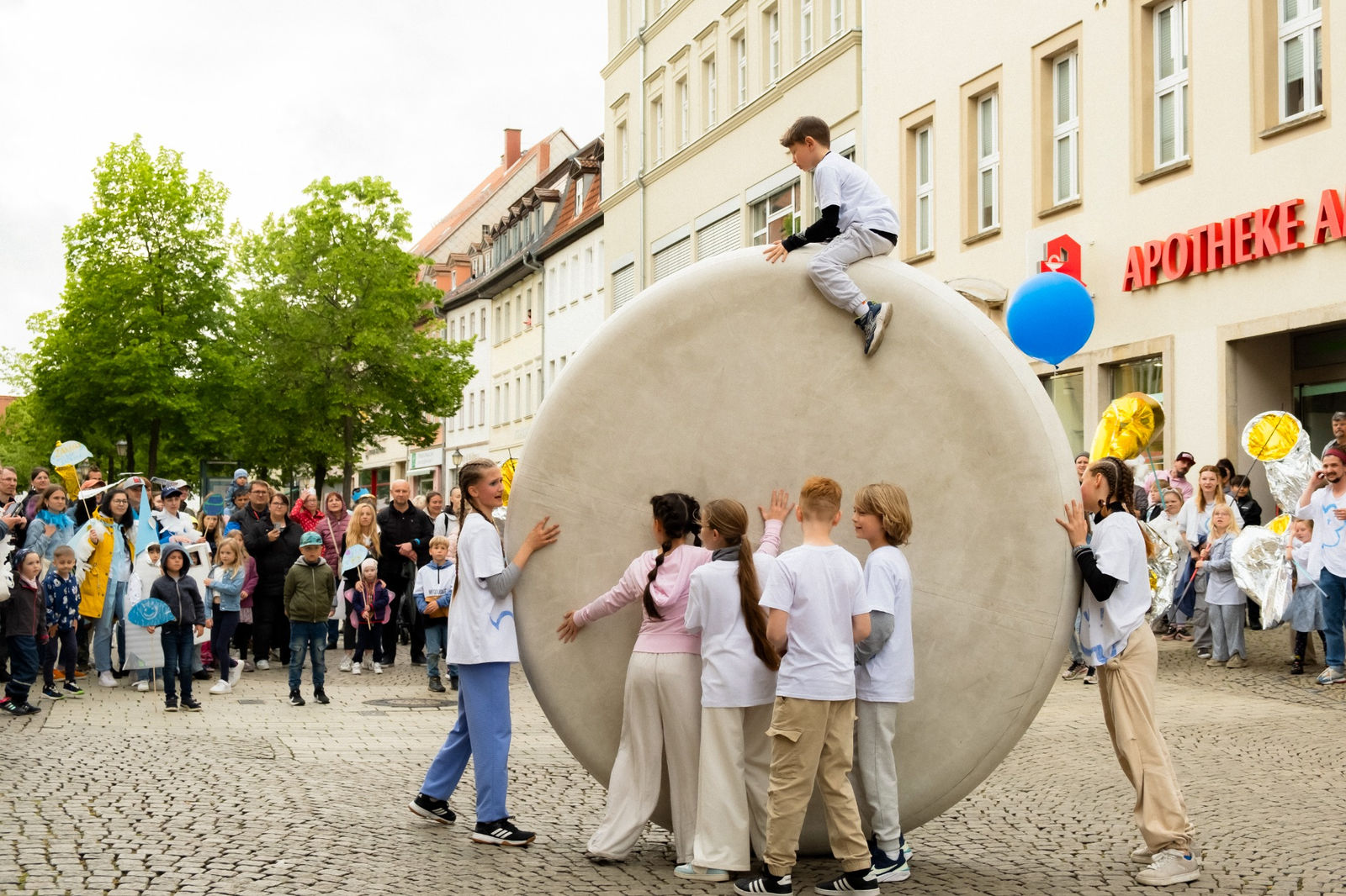 Kids rolling a giant ball through the streets