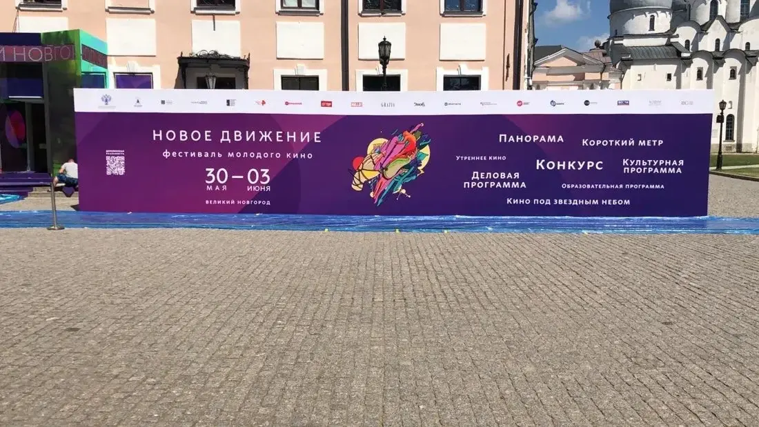 Уличный пресс-волл с фиолетовым баннером у фасада здания