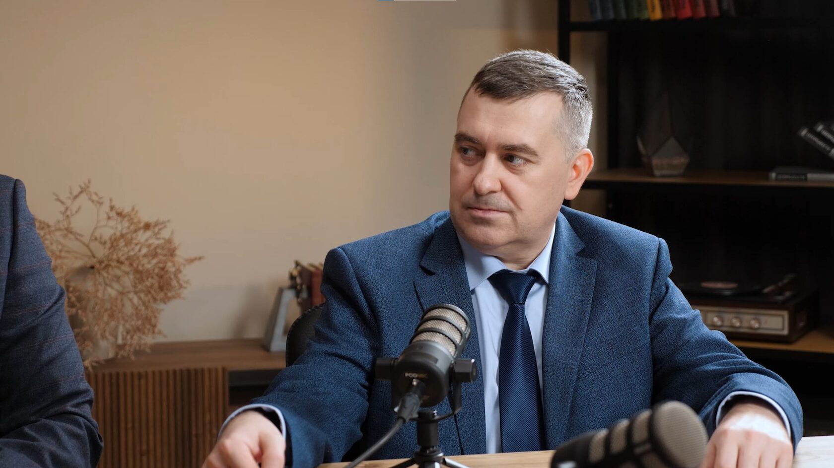 Человек за столом с микрофоном в студии подкастов