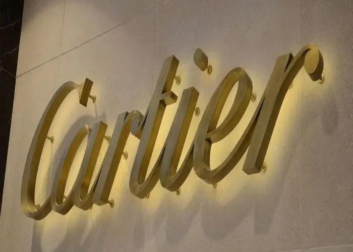 Интерьерная латунная надпись Cartier на светлой стене
