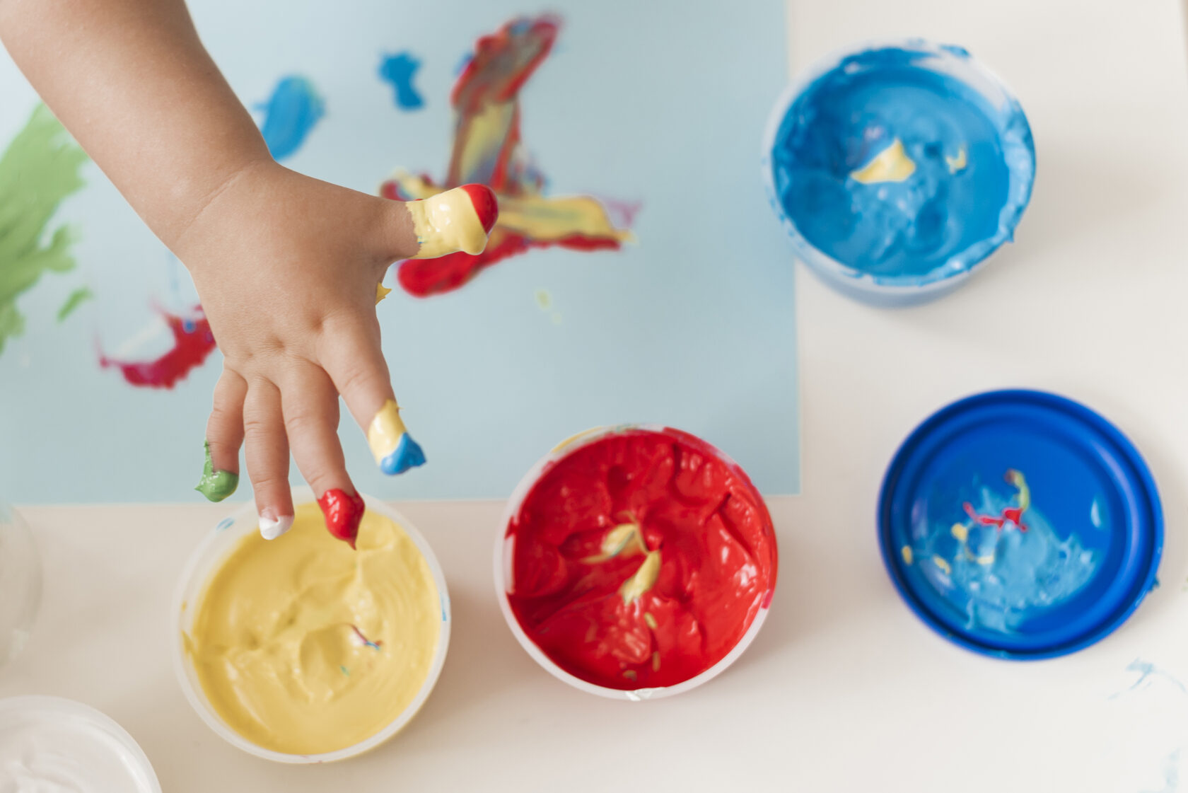 Baby’s hand exploring bright colors during sensory play to support early learning and motor skill development.