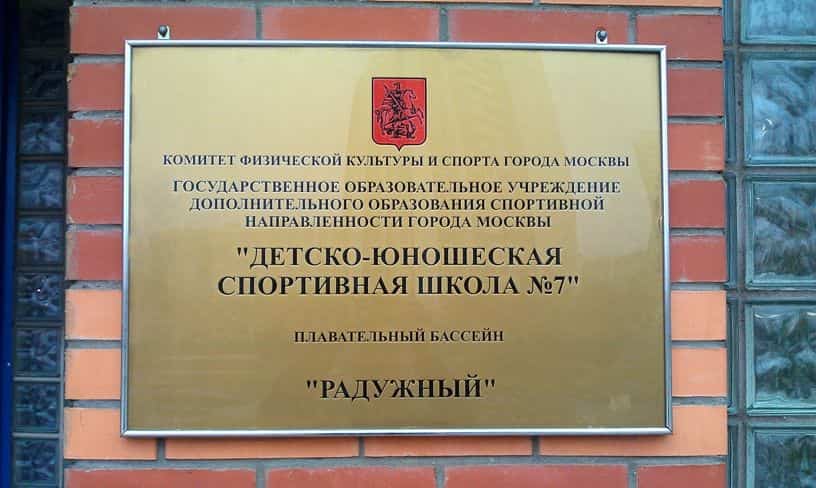 Фасадная табличка спортивной школы на кирпичной стене