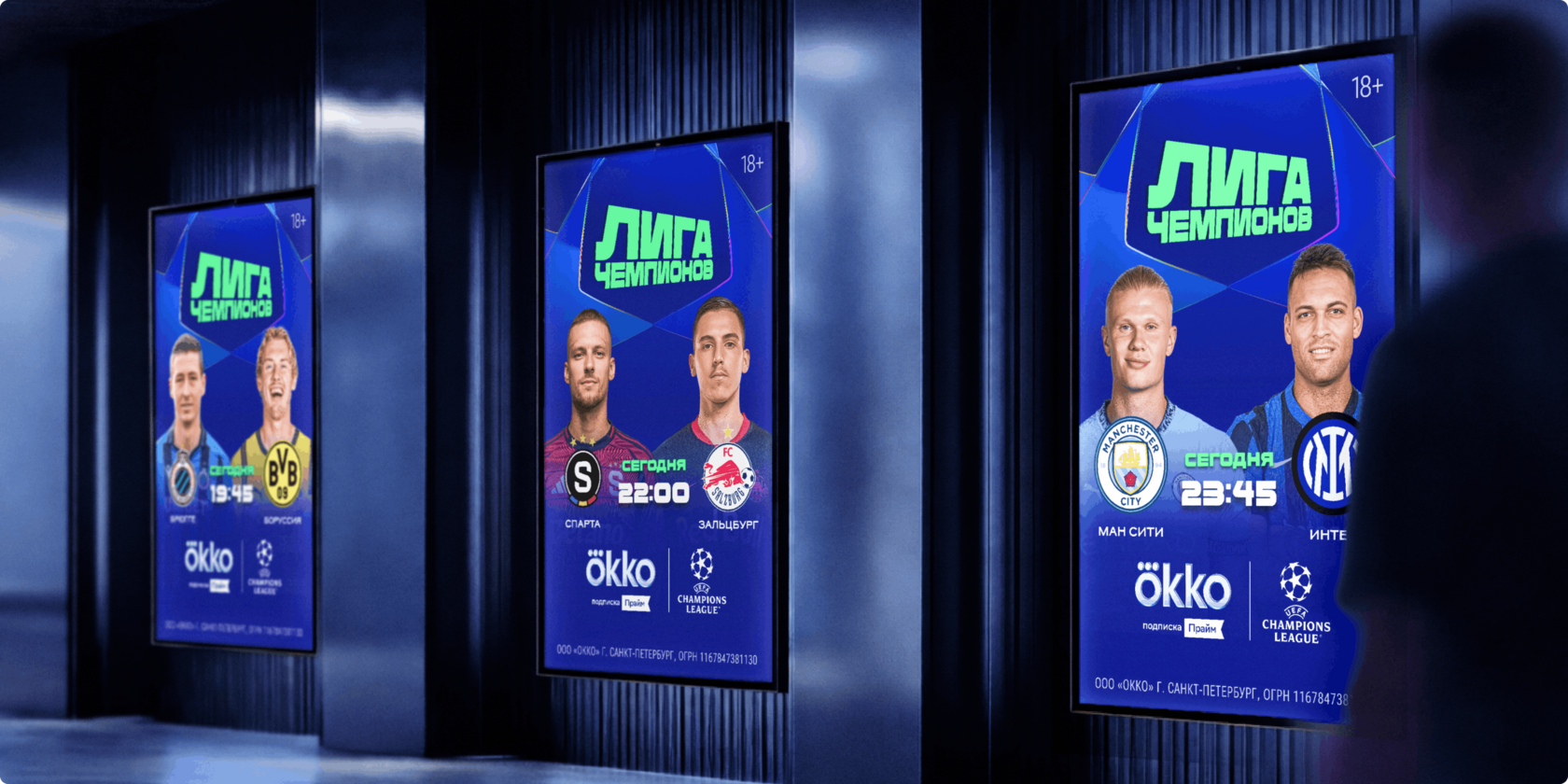 Айдентика Okko Sport: три вертикальных digital-экрана в городском интерьере с постерами Лиги чемпионов — лица футболистов, логотипы клубов, время начала матчей и брендинг Ökko/Champions League на синем фоне.
