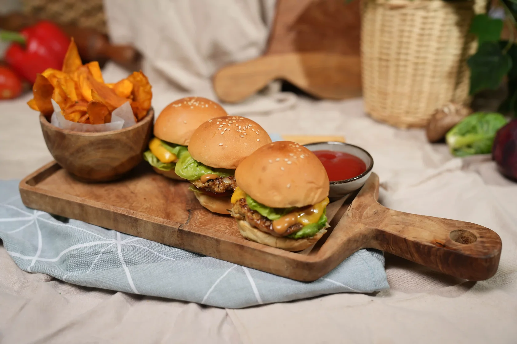 Three mini beef burger sliders with cheese, lettuce and tomato served with sweet potato chips