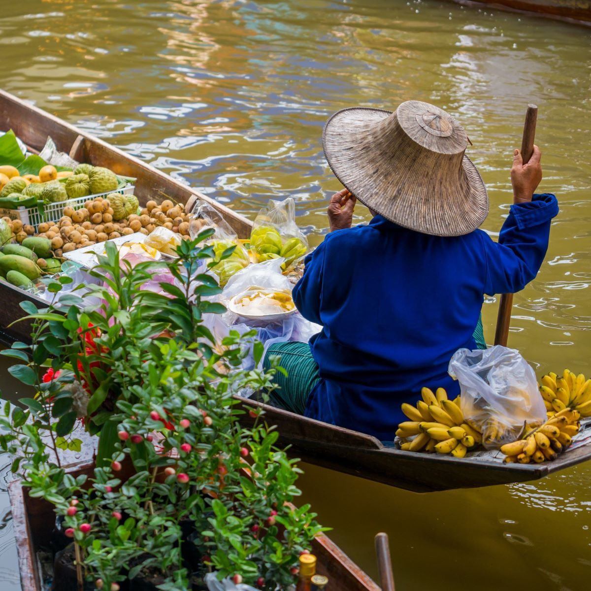 Traditional vendor selling fresh produce from a boat at Damnoen Saduak Floating Market in Thailand - Thai Travel Store