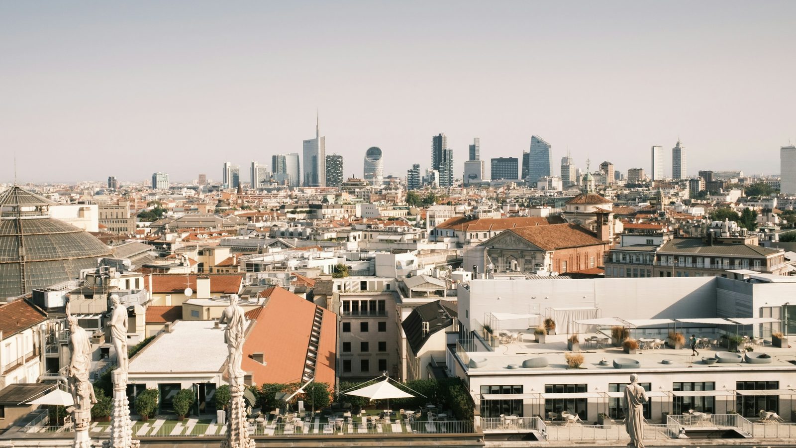 Milan skyline seen from a rooftop, with historic buildings in front and the Porta Nuova skyscrapers behind