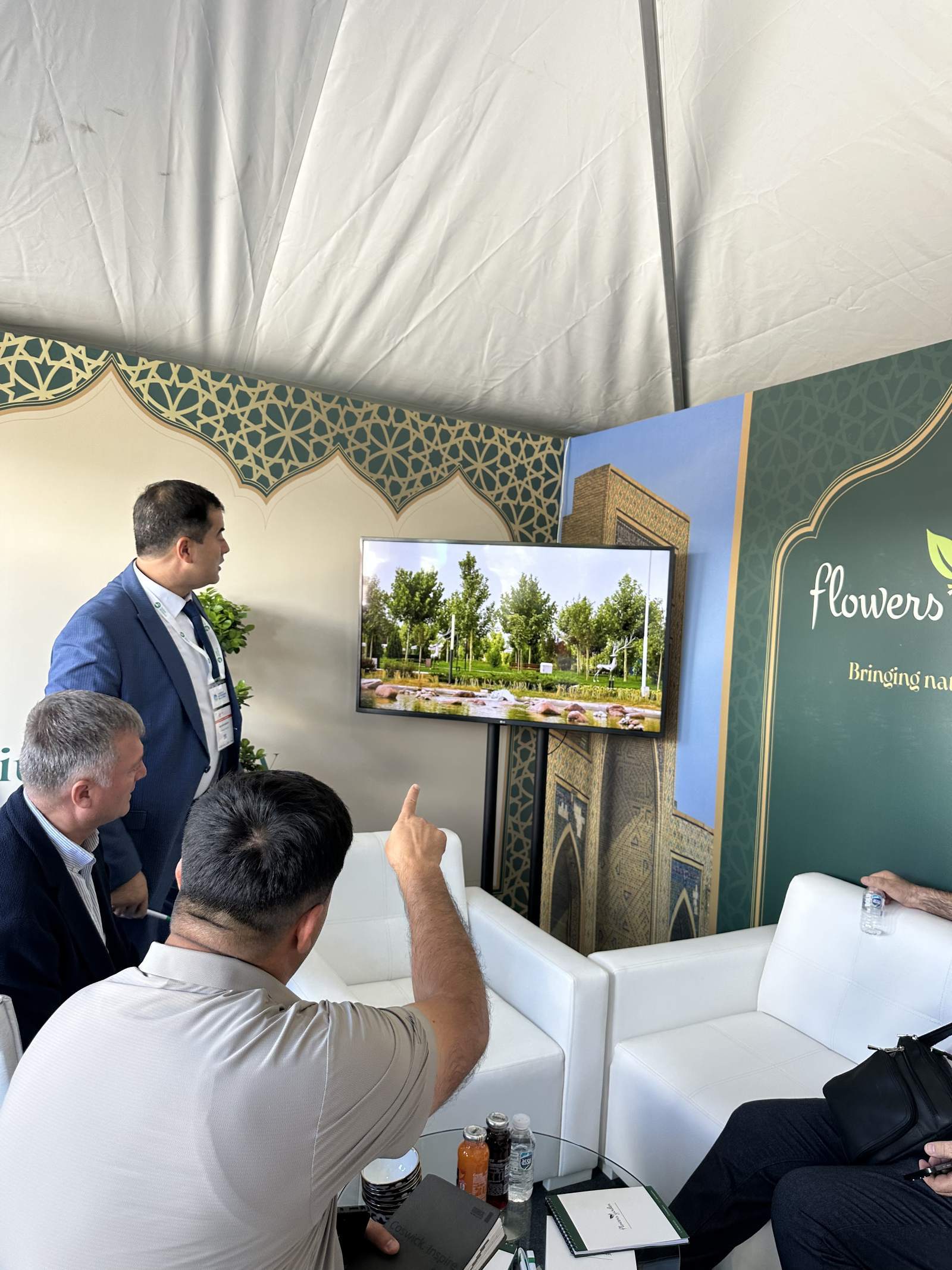 Представитель Flowers Garden показывает гостям реализованные проекты озеленения на экране
