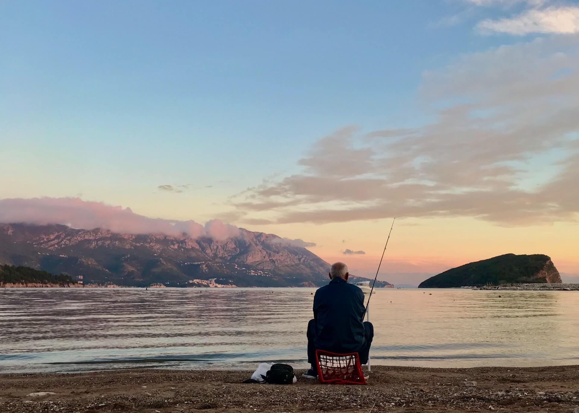 A Guide to Montenegro - A man fishing at sunset on the shores of Boka Bay